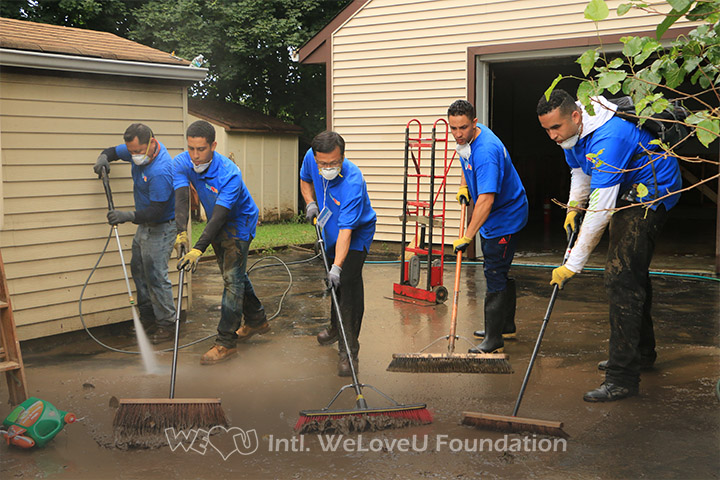 WeLoveU volunteers push away mud.