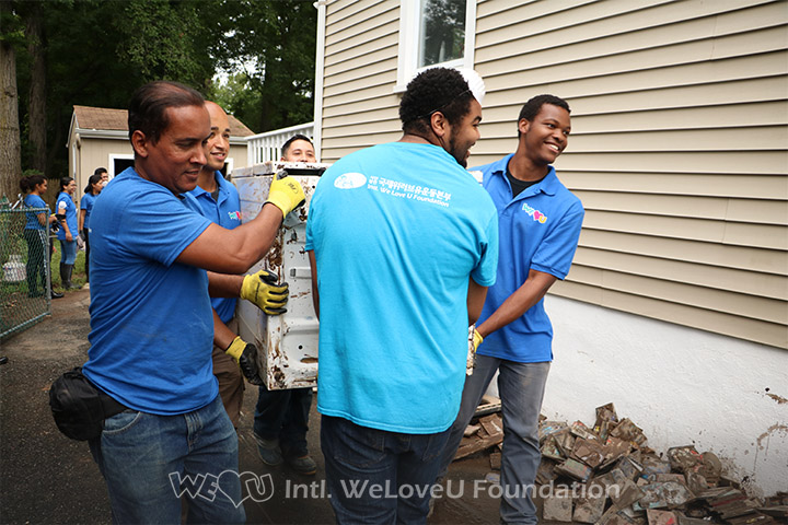 WeLoveU volunteers carry out damaged items from neighbors homes.