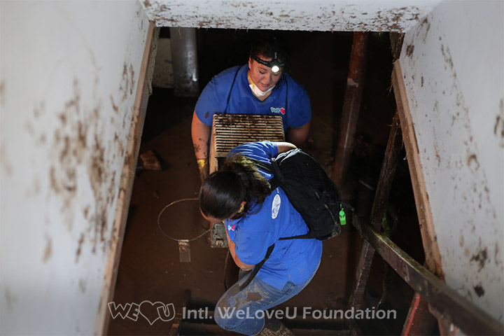 WeLoveU volunteers clear damaged items out of residents basements.