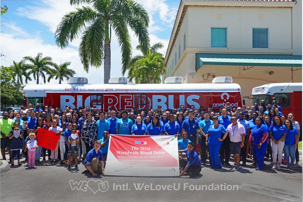 Volunteers who donated blood take group photo outside of OneBlood's donation bus