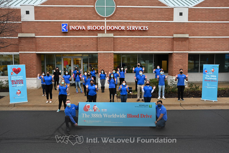 WeLoveU volunteers stand outside Inova Blood Donor Services in Virginia with a banner that says 388th Worldwide Blood Drive