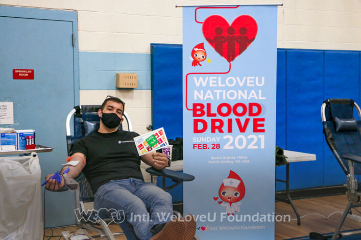 A person holds up a photo prop of the SDGs while donating blood in South Amboy