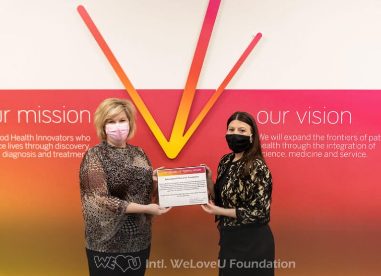 Versiti representative and WeLoveU volunteer hold the Certificate of Appreciation