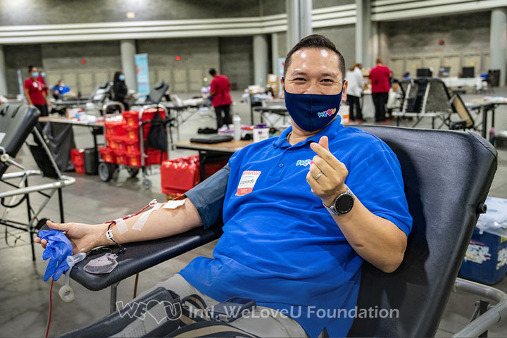 A happy volunteer smiles while donating blood at WeLoveU's blood drive in Atlanta, GA