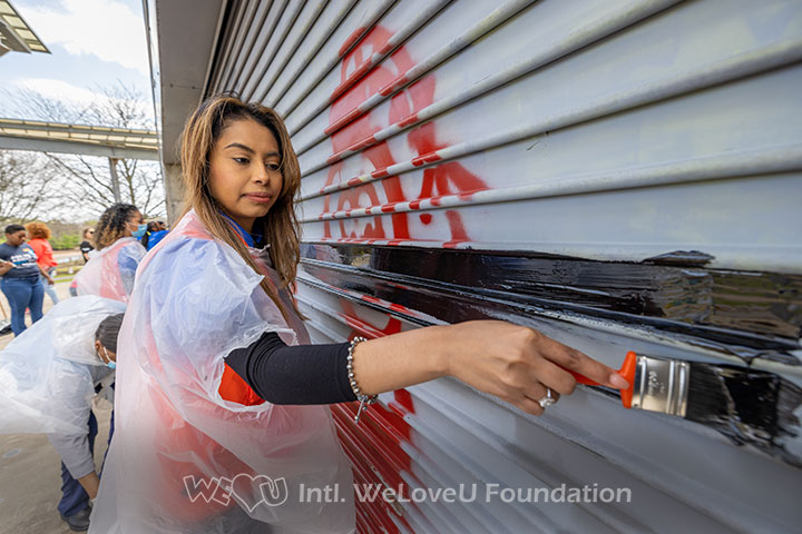 A WeLoveU volunteer paints over graffiti